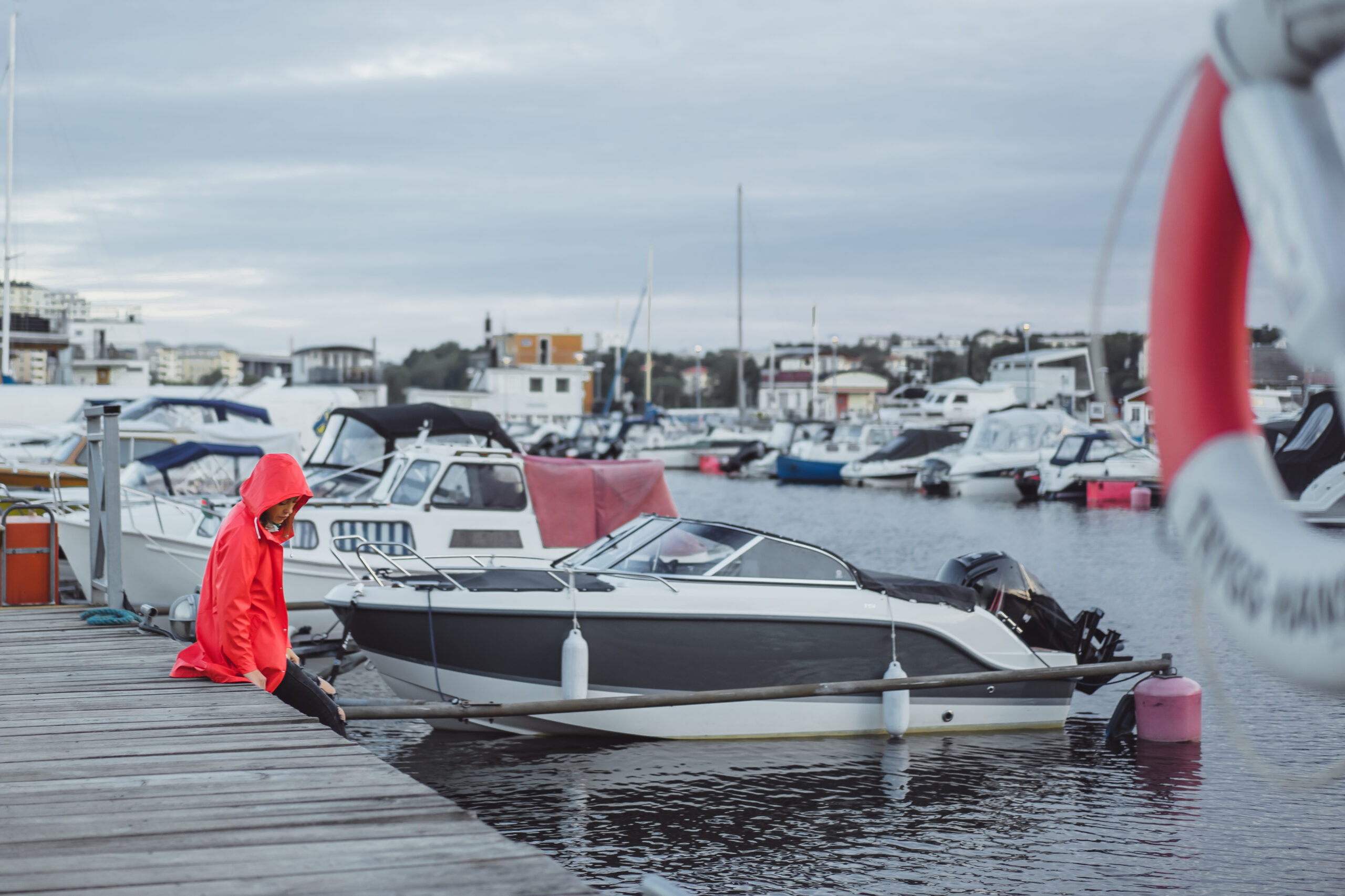 Beautiful young woman in a red cloak in the yacht port. Stockholm, Sweden